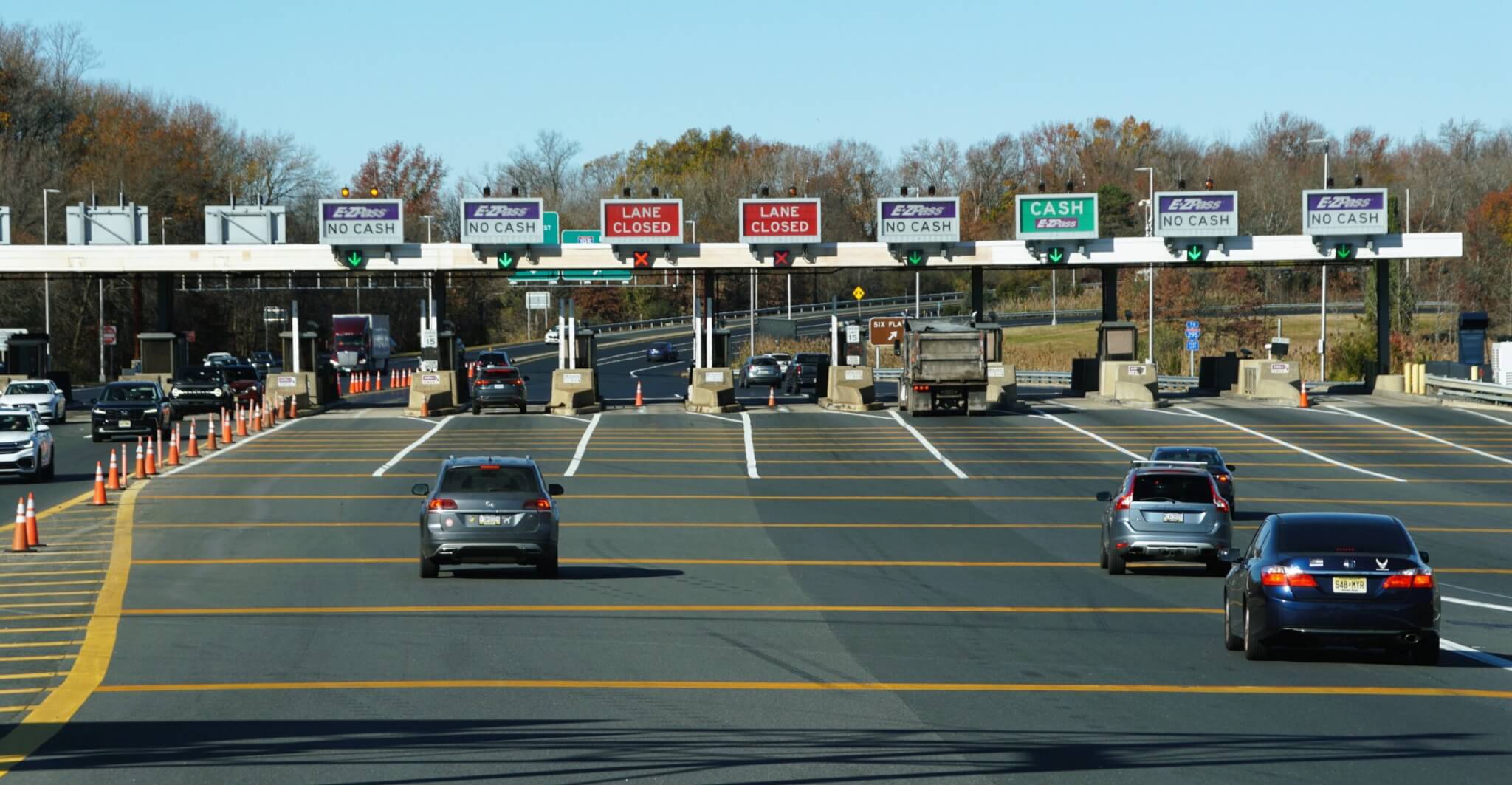 Traffic flows through a toll plaza, with signs indicating E-ZPass and closed lanes.