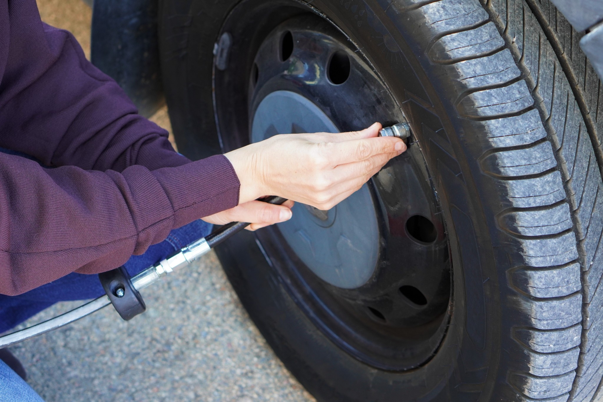 woman's hands checking the air pressure of her camper van's tires before the trip