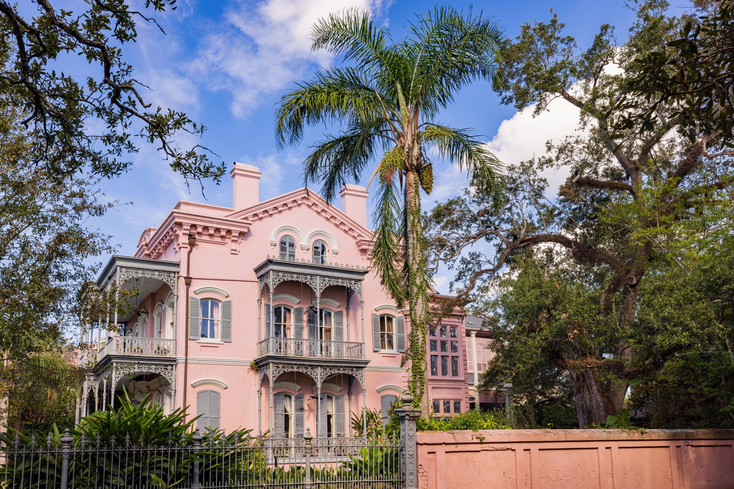 Colorful 19th-century mansions and historic homes line a quiet street in the Garden District of New Orleans, Louisiana.