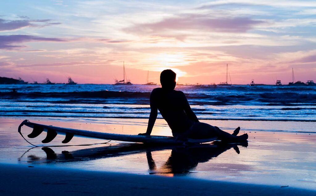 Surfer watching the sun set at Tamarindo, Costa Rica