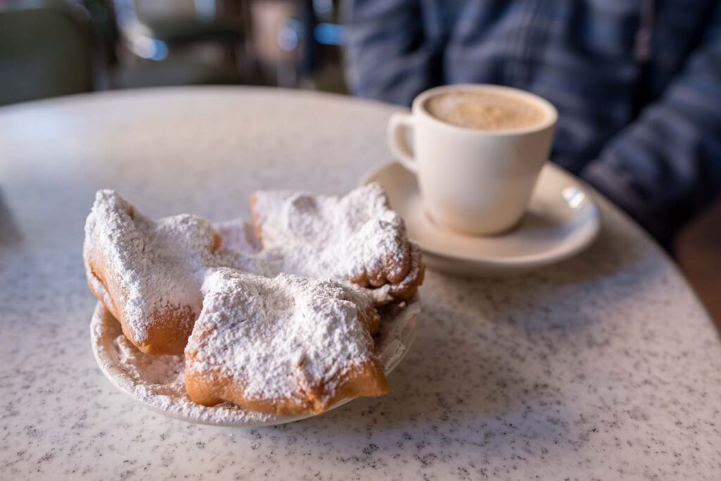 Beignets covered with powdered sugar, served with cafe au lait at the famous Cafe Du Monde in the French Quarter. 