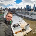 Young man takes selfie with huge cruise ship and New York city in the background