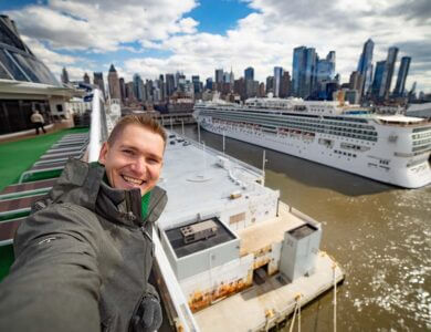 Young man takes selfie with huge cruise ship and New York city in the background