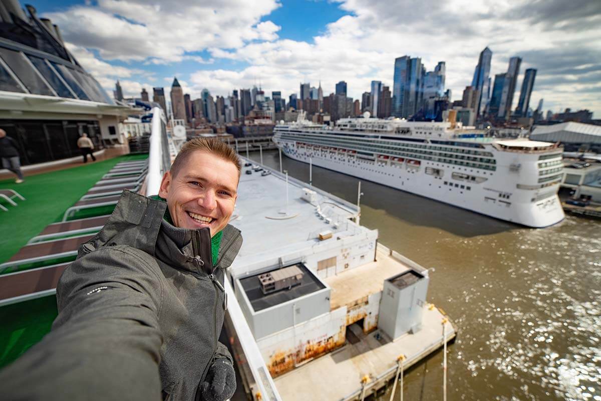 Young man takes selfie with huge cruise ship and New York city in the background