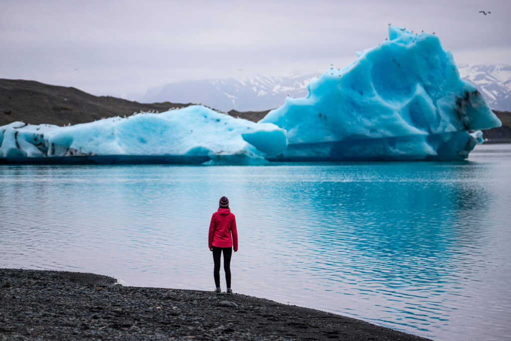 A girl wearing an Icelandic wool cap admires the unique blue icebergs on Lake Jökulsárlón, a unique glacial lake at the Vatnajökull glacier