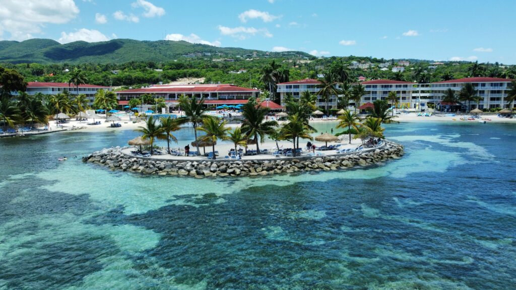 Aerial of hotels on a beach covered with greenery against a turquoise sea in Montego Bay, Jamaica