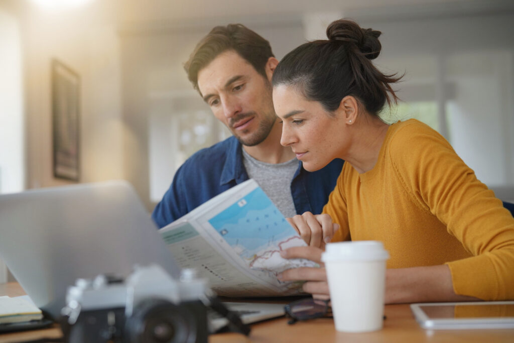 Attractive couple planning their trip looking at map at home