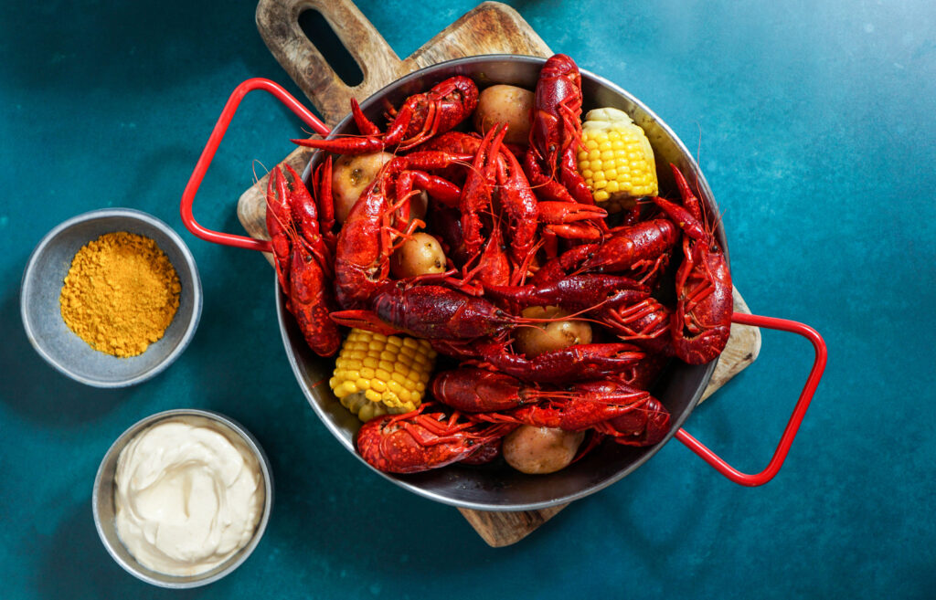 Crawfish boiled Louisiana,with corn on the cob, potatoes. Crawfish boiled in Cajun seasonings and herbs.with beer, New Orleans, Cajun or Creole cuisine, blue background
