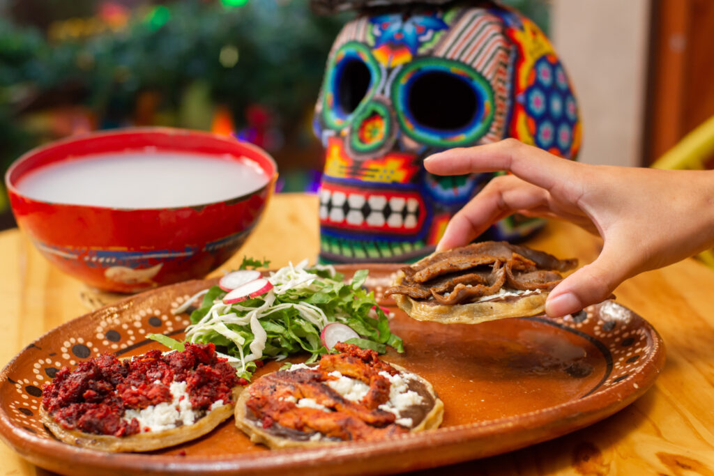 hand taking Mexican meat sopes from traditional dia de muertos offering