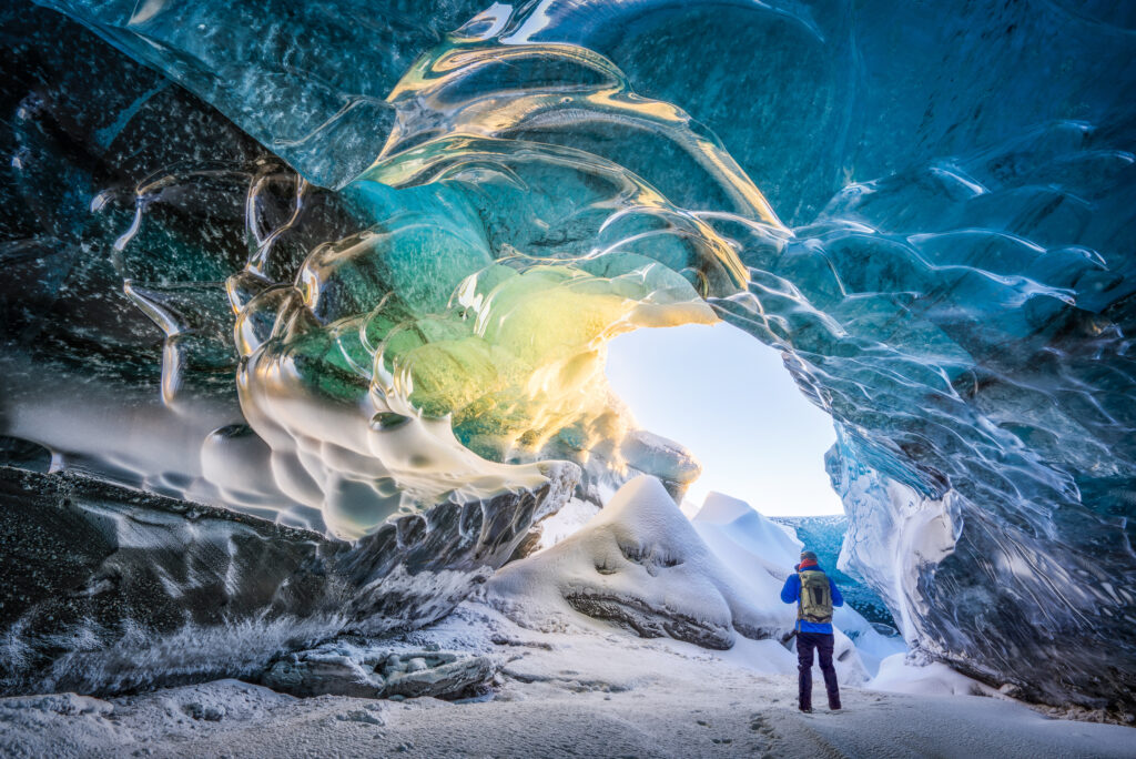 Hiker exploring ice cave, iceland