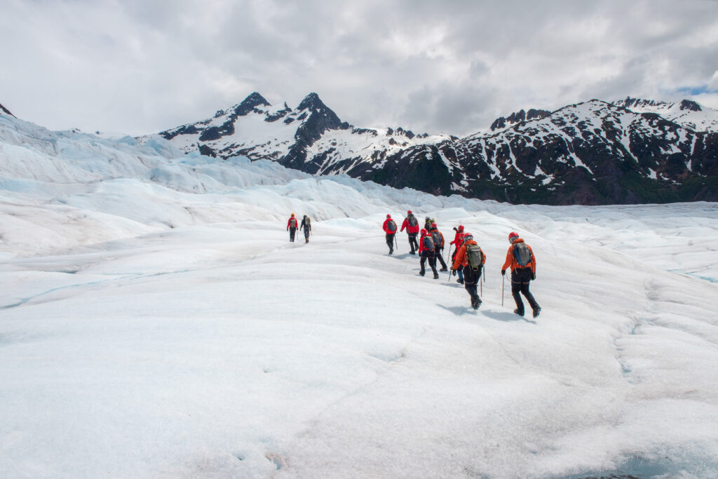 Hikers on a glacier surrounded by mountains in Alaska