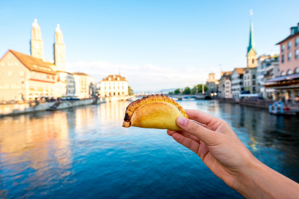 Holding a small pie on Zurich cityscape background. Street food and quick snack in Switzerland