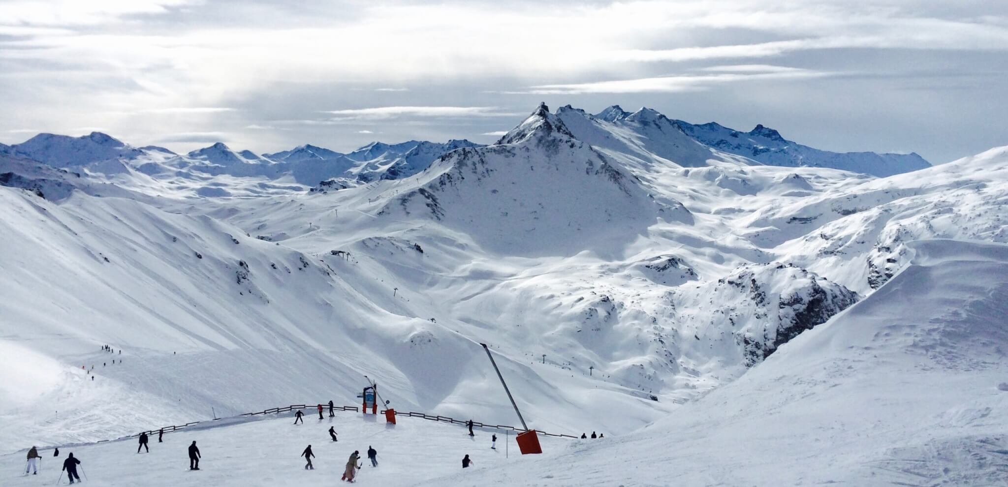 People lurking around on snow field near mountains