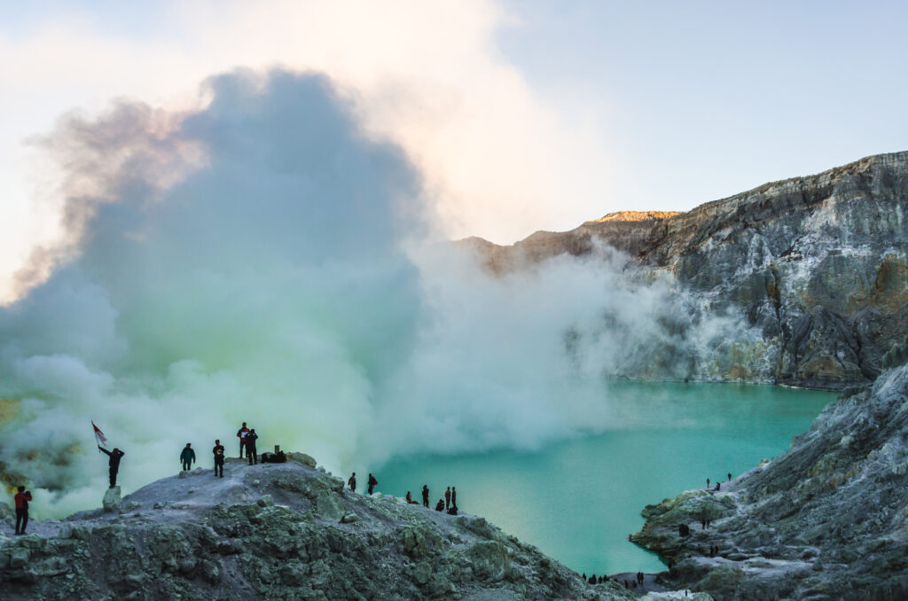 Posing for photos at sunrise with the smoking sulphuric cloud of mount Ijen behind