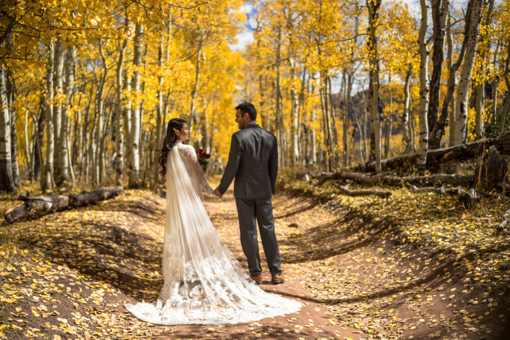 Wedding/engagement photography - Beautiful Asian/Vietnamese bride in wedding dress with caucasian groom in the beautiful fall/autumn yellow leaves.  Colorado Rocky Mountains.  Aspen, Colorado.  USA