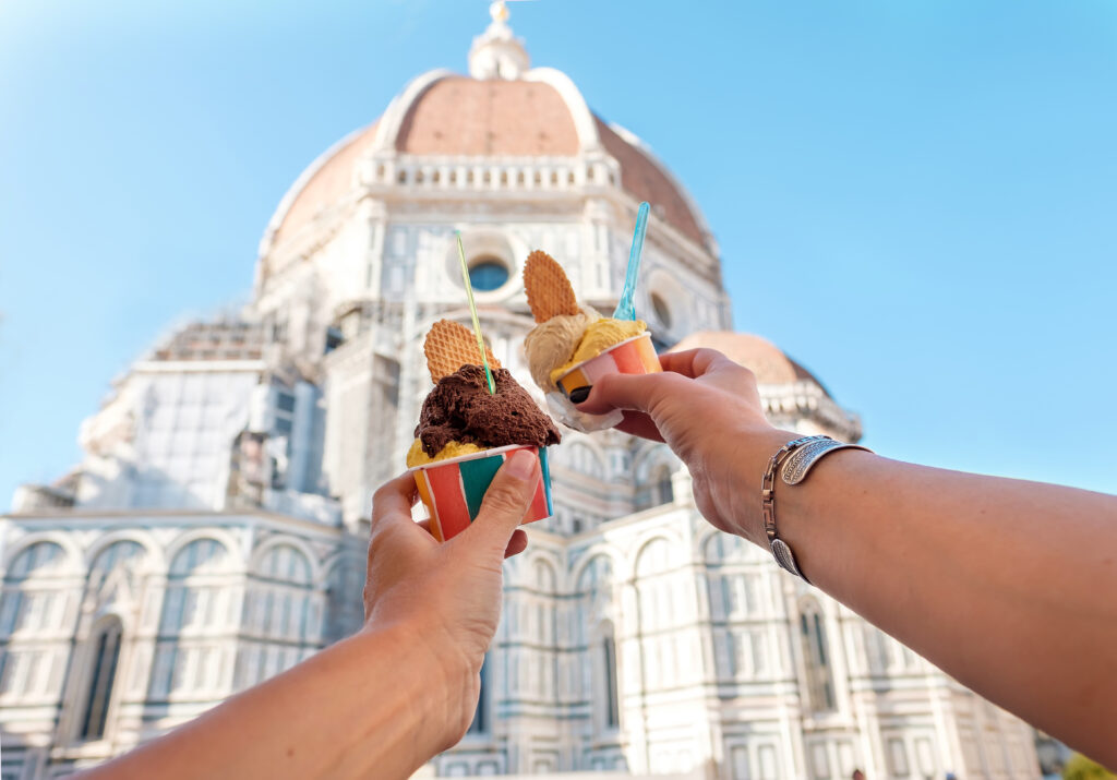 Women's hands with ice cream Gelato on the background of the city sight Cathedral of Santa Maria del Fiore in the historical center of Florence, Italy, Europe, a famous tourist place