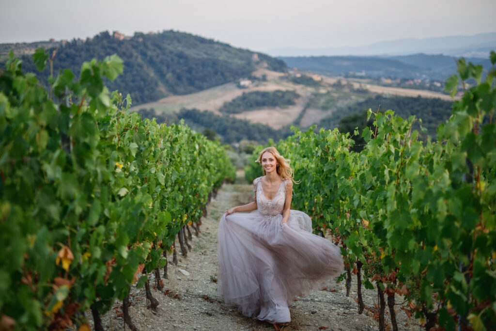 young beautiful wedding bride walks at sunset in Tuscany in Italy near the vineyards in a beautiful dress