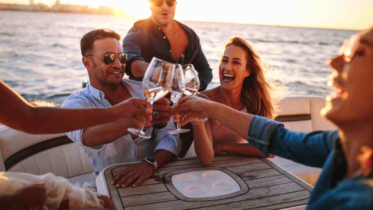 a group of people toasting on a boat at sunset