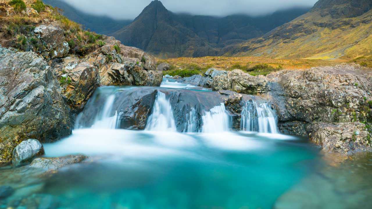 waterfall in the scottish highlands with mountains in the background