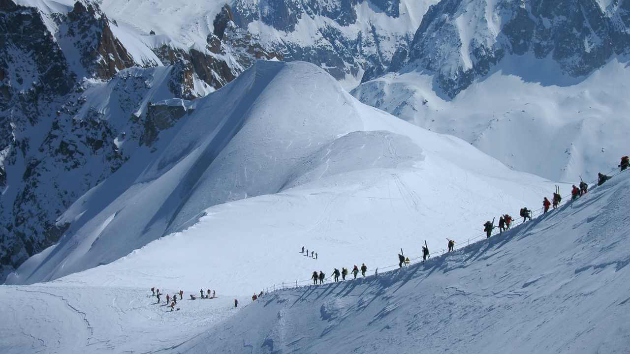 a group of people walking up a snow covered mountain