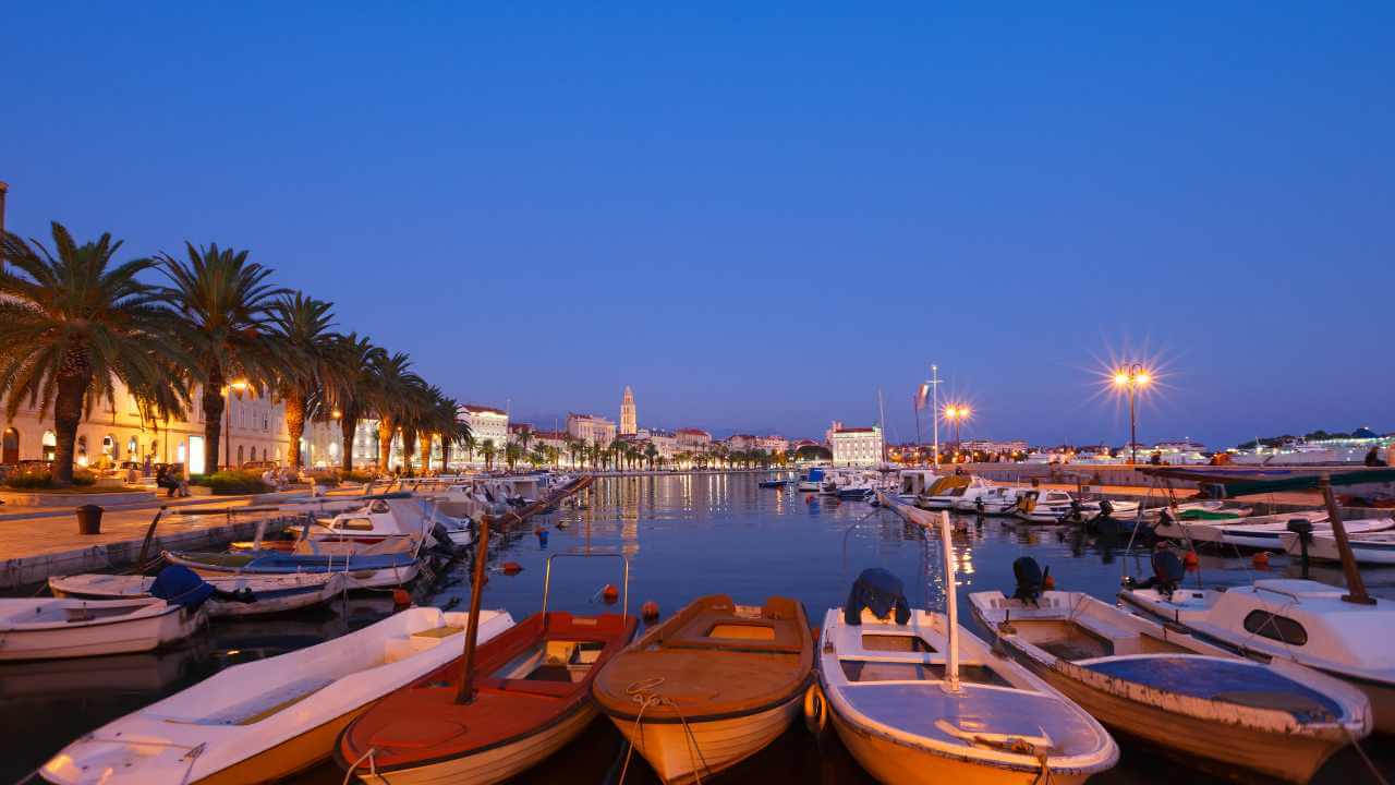 several small boats are docked in the water at night