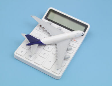 Airplane tickets price and travel budget concept. Airplane model and white calculator on blue background.