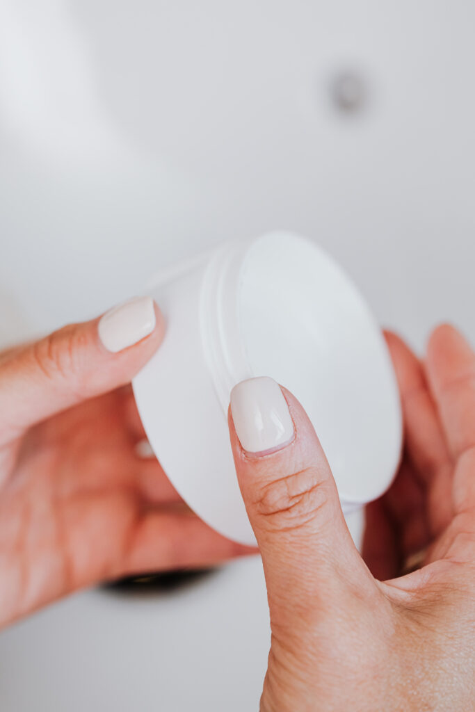 Person holding white round plastic container