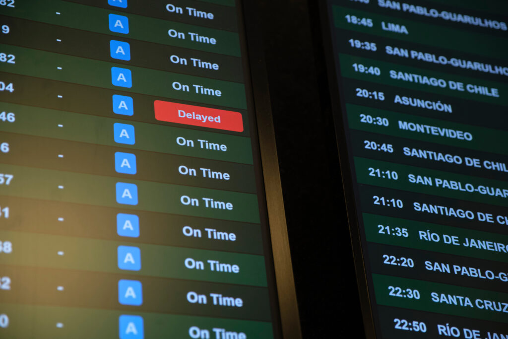 Screen with information on international flight departures, all are on schedule except one, marked in red, which indicates that it is delayed.