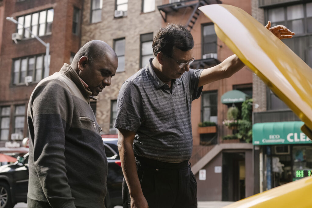 Serious ethnic men checking engine of car