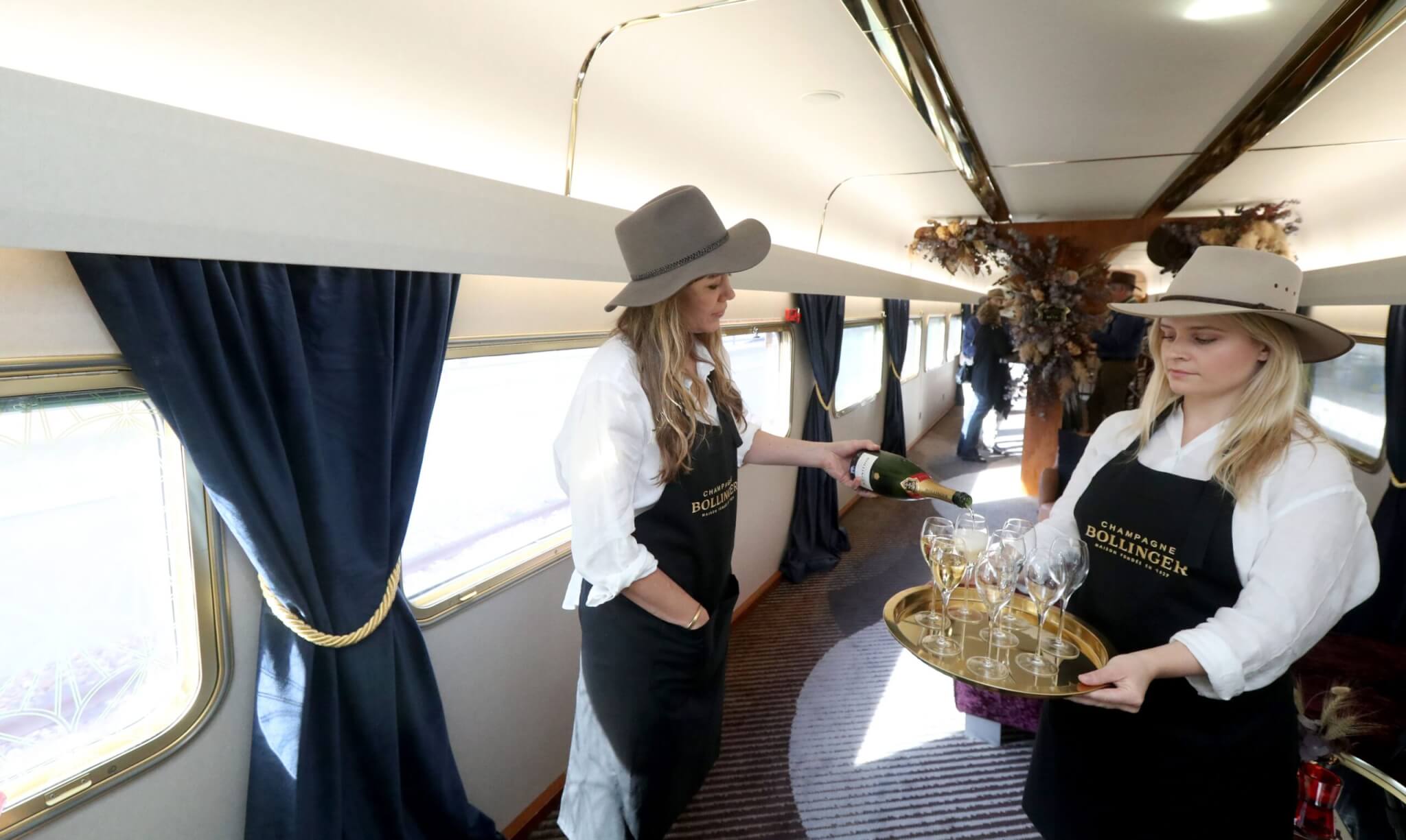 Cabin crew of Australian passenger train The Ghan serve champaign before leaving for Darwin in Adelaide, South Australia, Australia, 04 August 2019. The Ghan train service marks 90 years of operations on 04 August 2019, with a special service leaving Adelaide for Darwin. The transcontinental railway service runs between the cities of Adelaide, Alice Springs and Darwin traveling on the Adelaide-Darwin railway for 2,979 km.