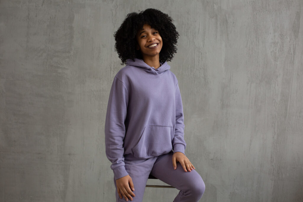 Smiling black woman in hooded sweatshirt sitting on high chair