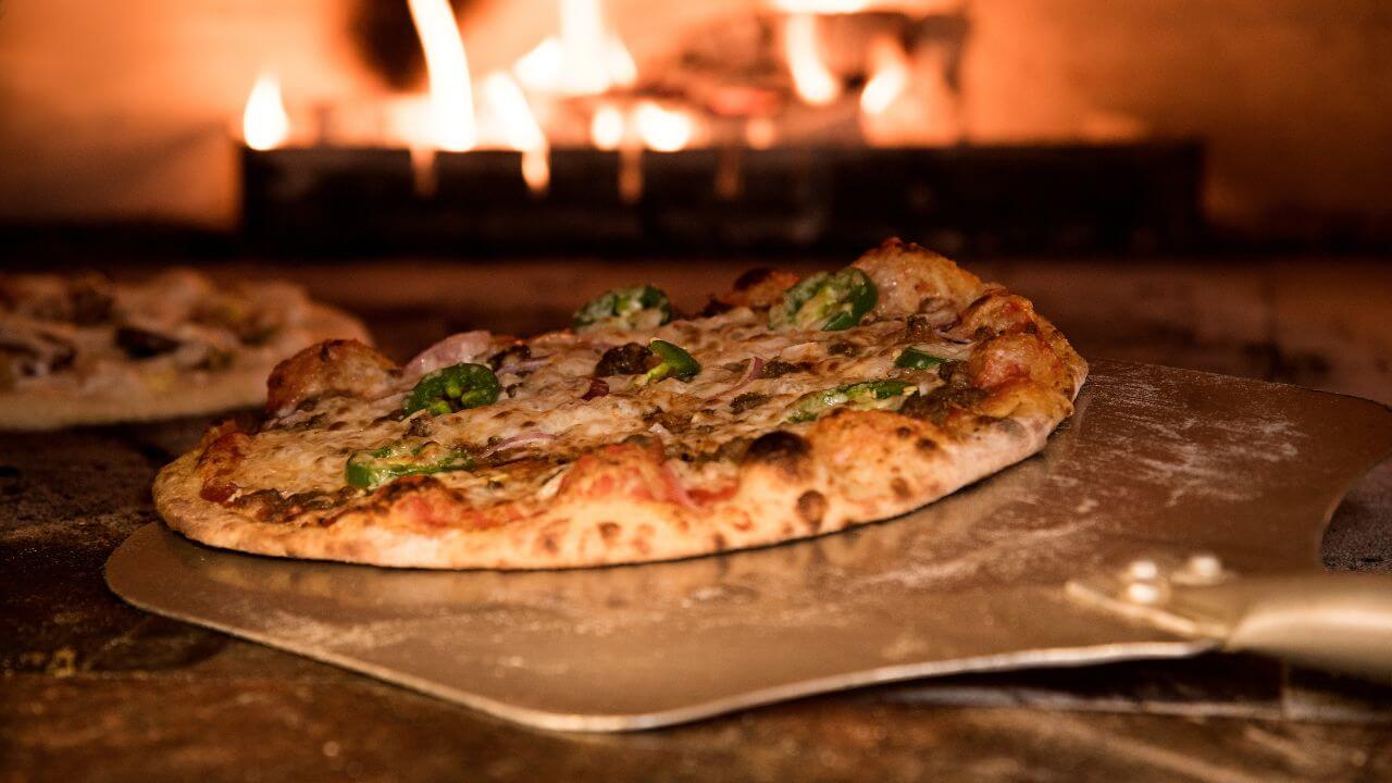 a pizza is being cooked in front of an open fire