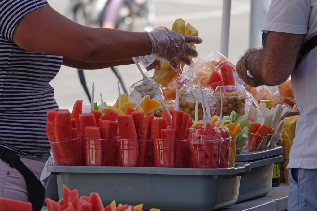 A food vendor sells fruit on a sidewalk in Los Angeles during a summer day.