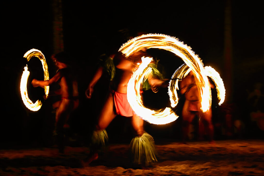 Fire dancers at Hawaii luau show, polynesian hula dance men jugging with fire torches.