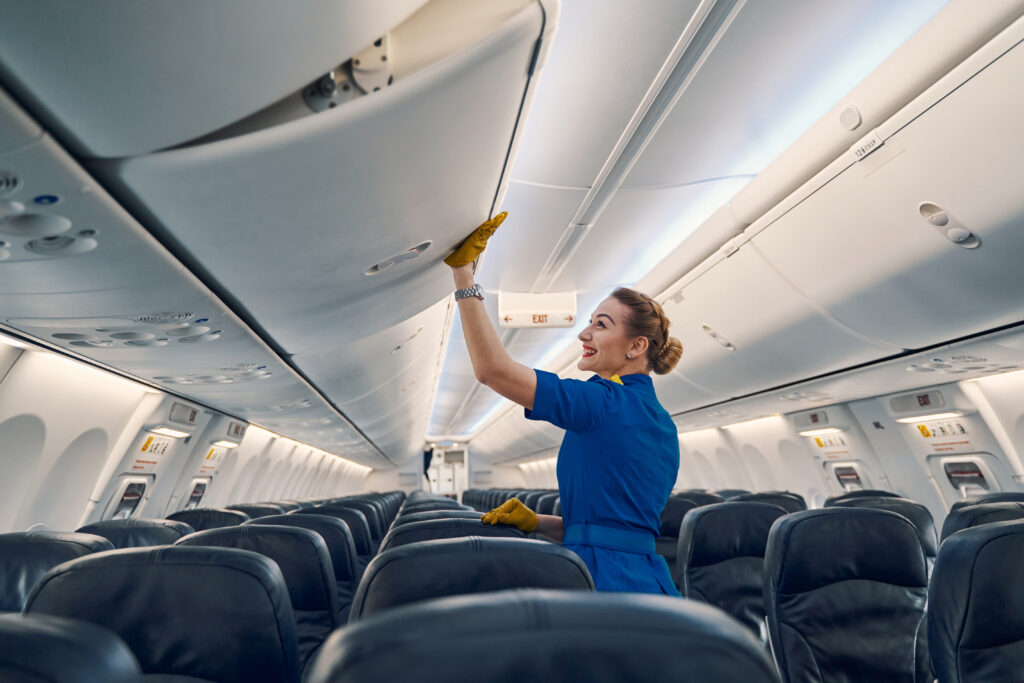 High-spirited air hostess in leather gloves shutting an overhead locker