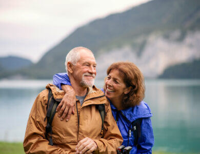 Senior pensioner couple hiking by lake in nature, resting.