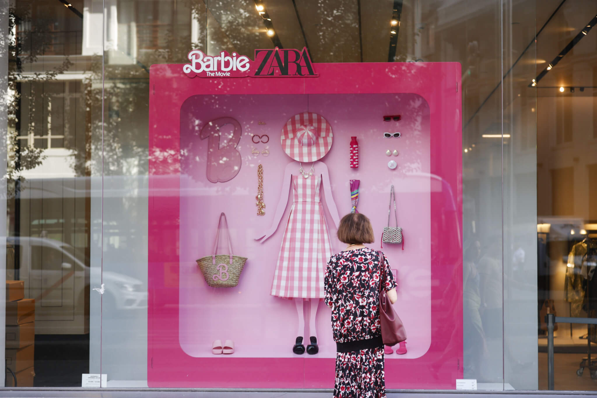 A passer-by looks at an outfit of the 'Barbie' collection at a Zara store's shopping window in Madrid, Spain, 20 July 2023. The brand's collection, which is inspired by the fashion doll  of American toy company Mattel, Inc., is presented on the same day of the premiere of the movie 'Barbie' in Spanish cinemas.