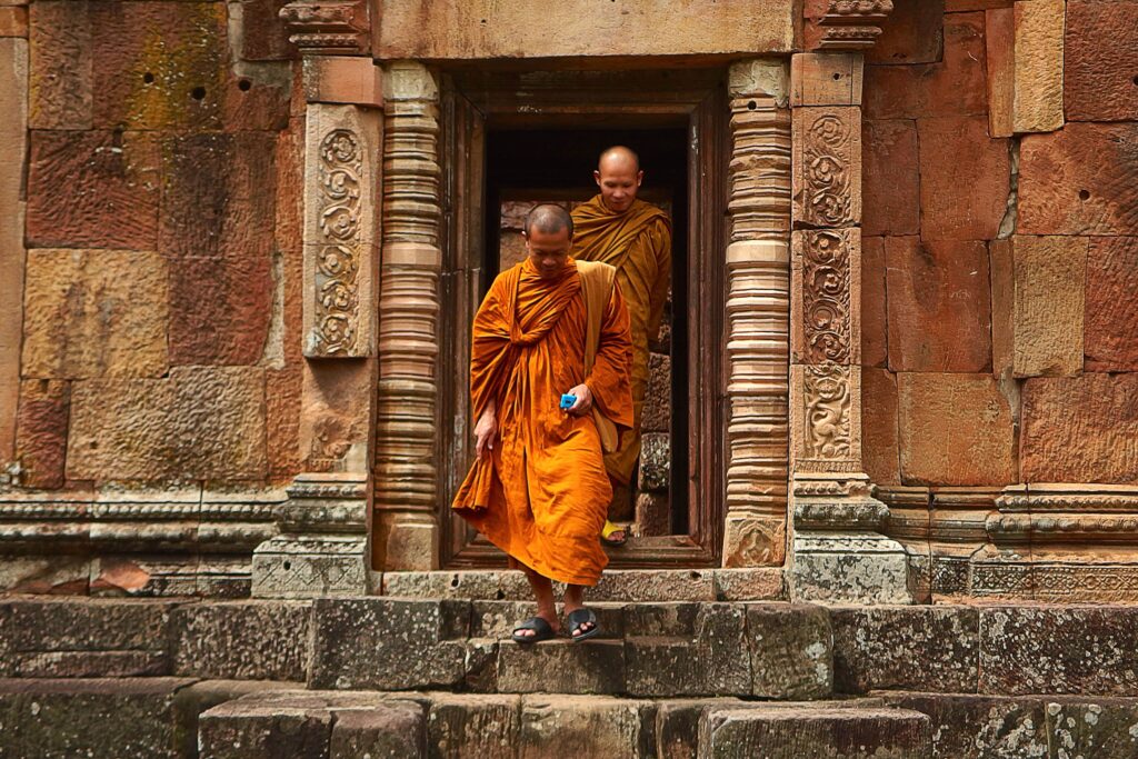 Two monk in orange robe walking down the concrete stairs