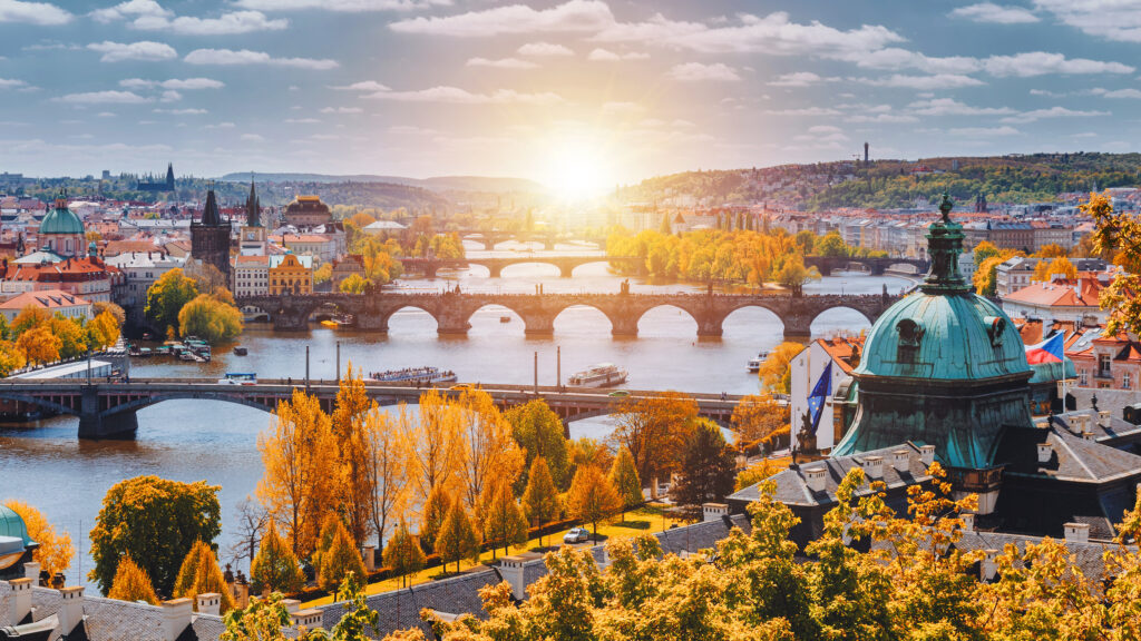 View to the historical bridges, Prague old town and Vltava river from popular view point in the Letna park (Letenske sady), beautiful autumn landscape in soft yellow light, Czech Republic
