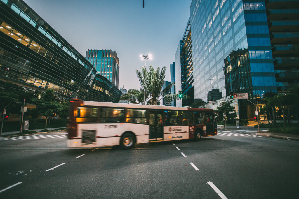 White bus on road near in high rise building during daytime