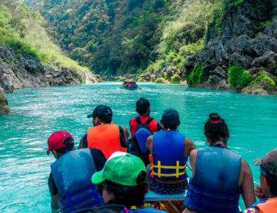 A group of people in lifejackets sailing on a turquoise river