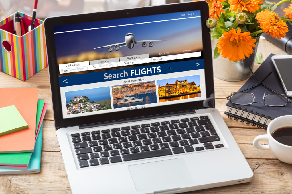 Search flights on a computer laptop screen, office desk background