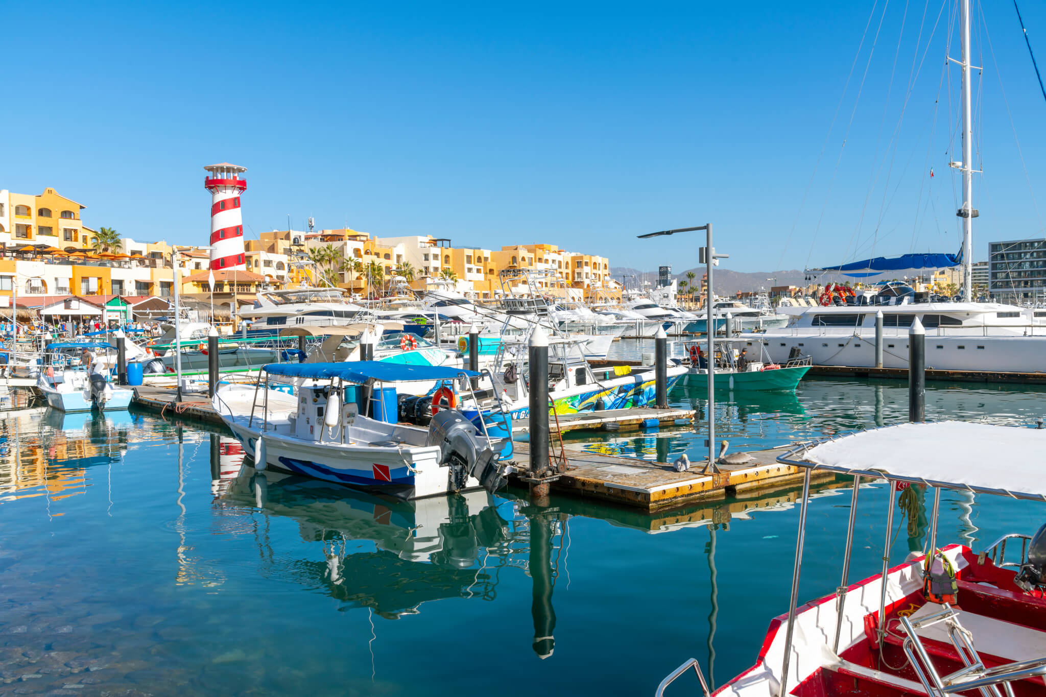 The colorful and busy cruise port with shops, cafes and boats in the marina along the Mexican Riviera at Cabo San Lucas, Mexico.