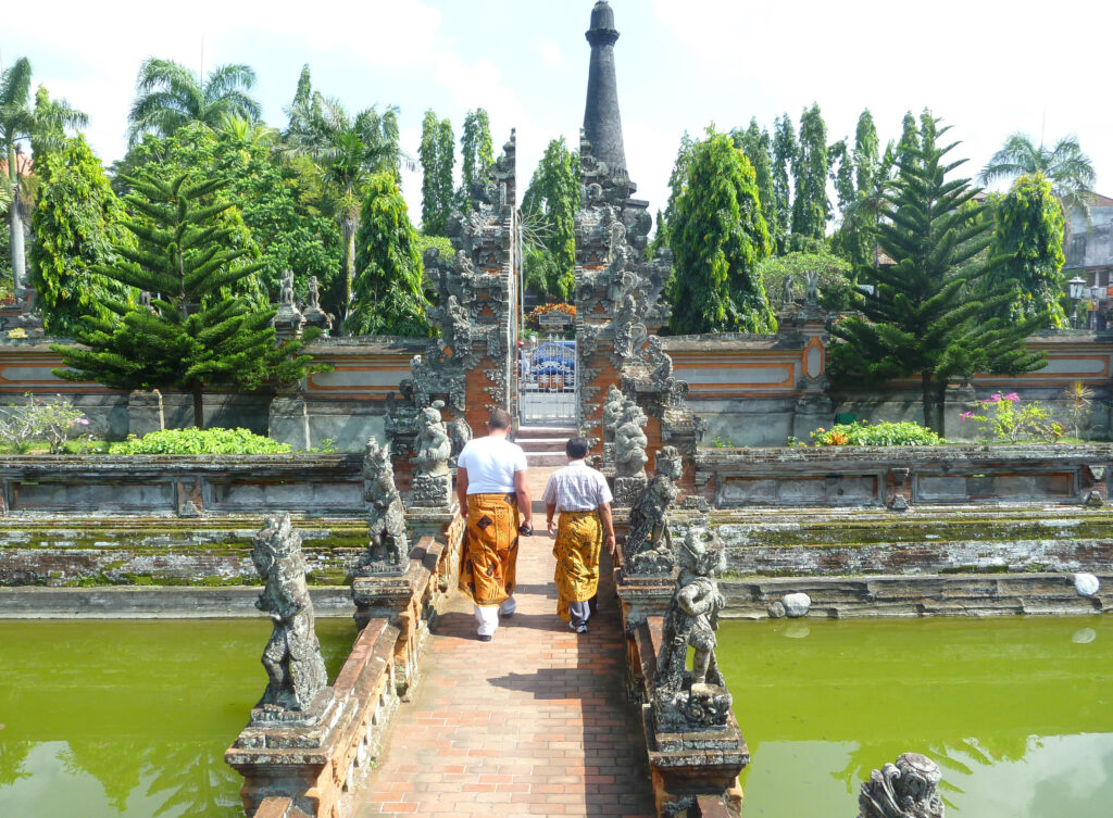 Two men put on sarongs in Bali a picturesque place a temple a Park the reservoirs of the green swampy water