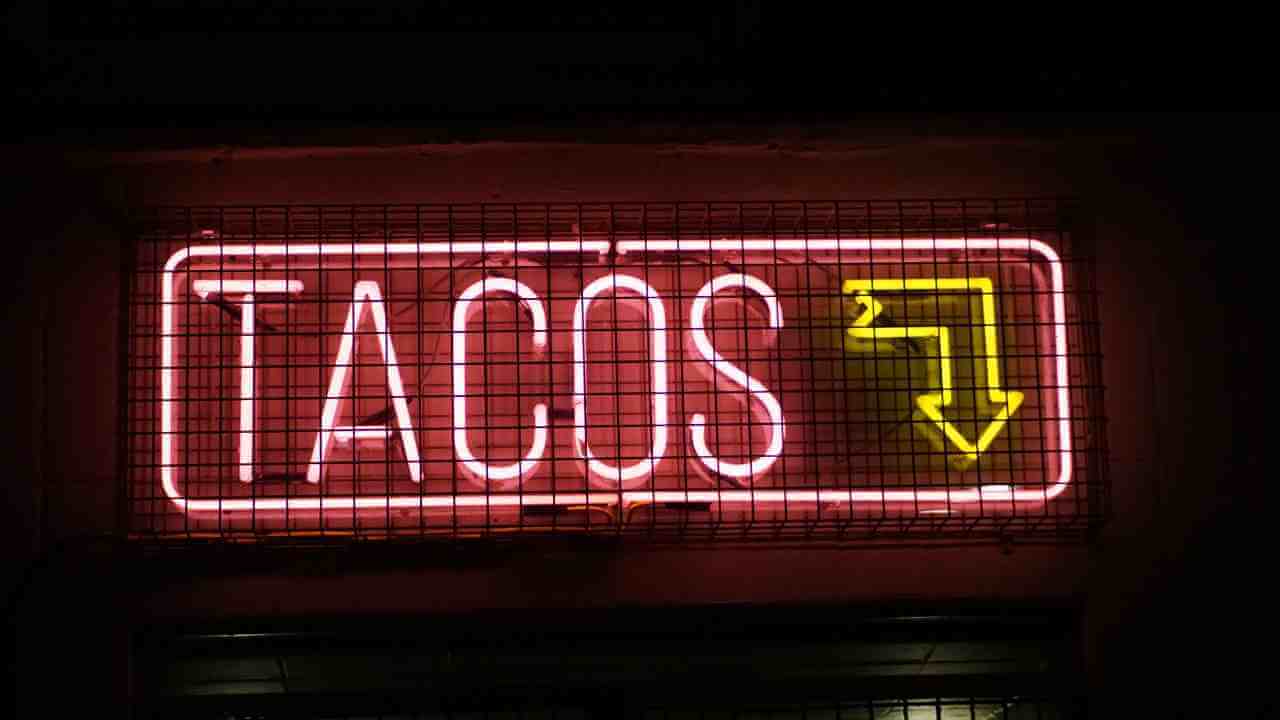 a neon sign that says tacos in front of a building