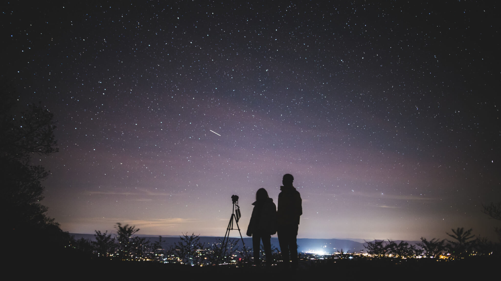 Silhouette of two persons stargazing