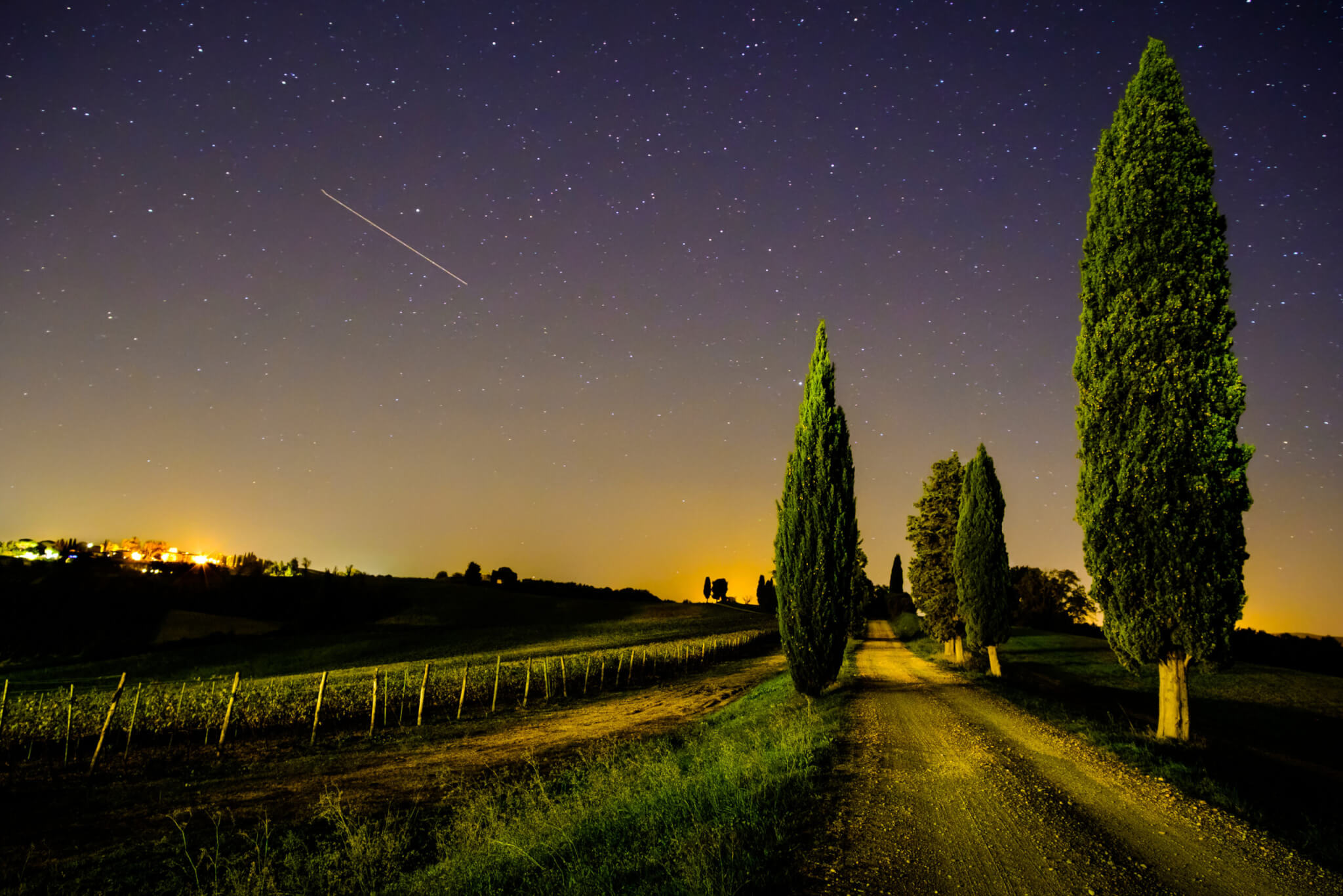 View of Tuscany vineyard and country road with shooting star in the sky
