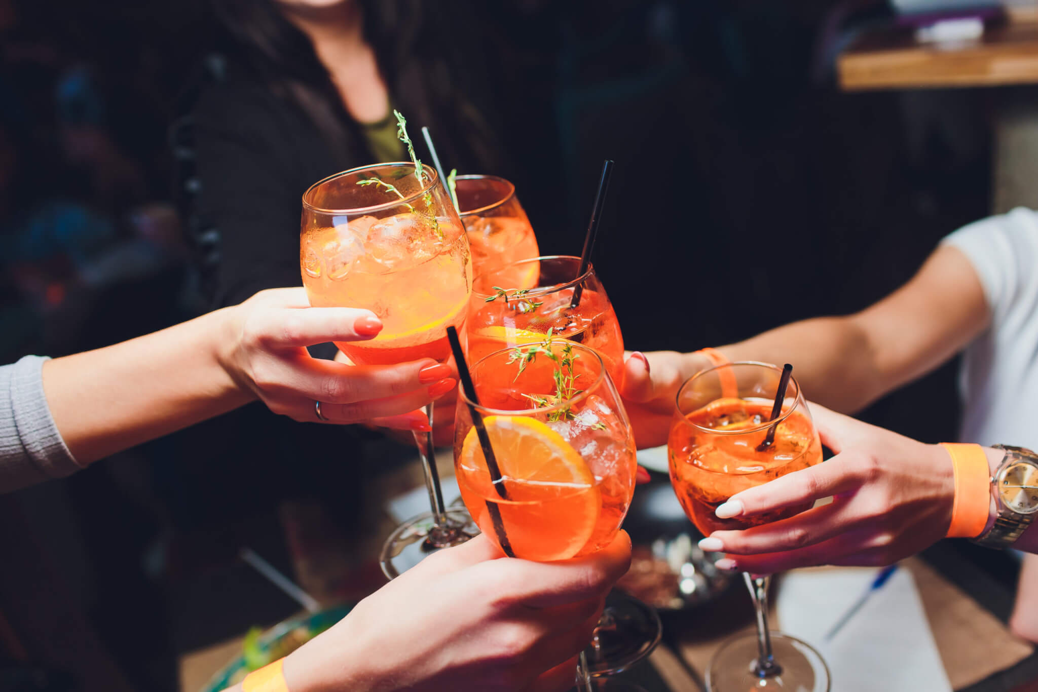 women raising a glasses of aperol spritz at the dinner table.