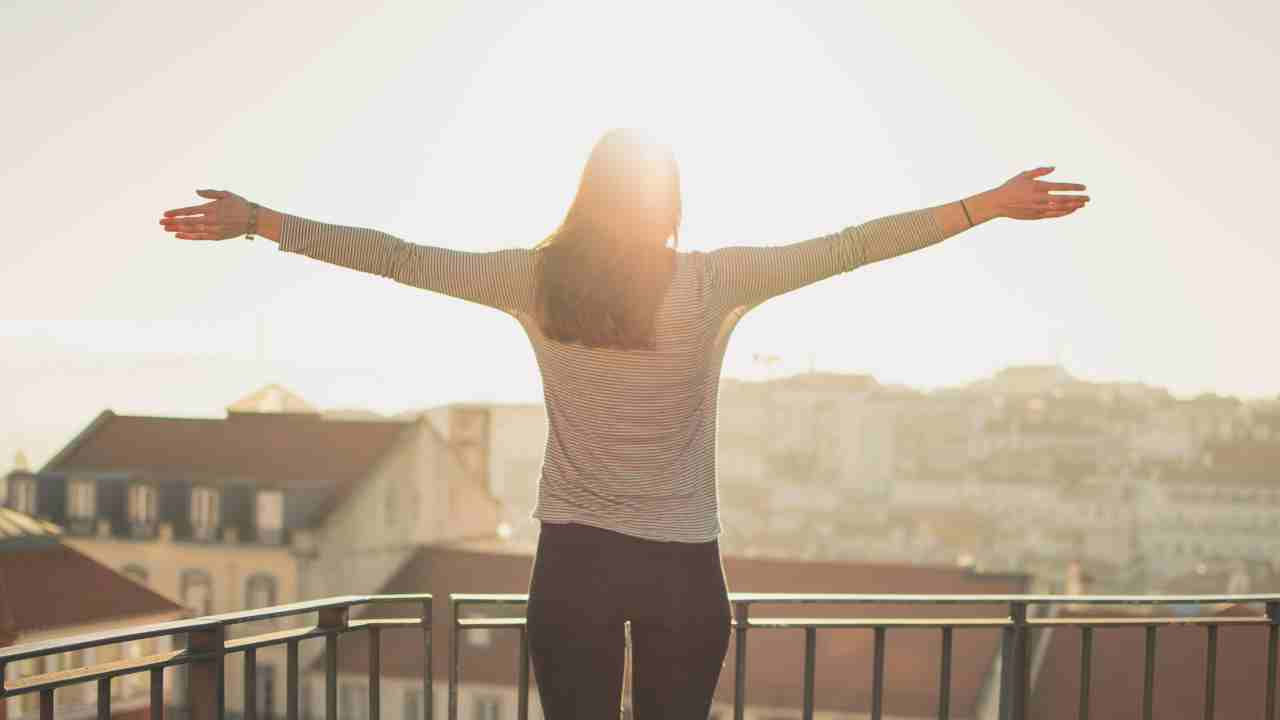 a person standing on a balcony with their arms outstretched