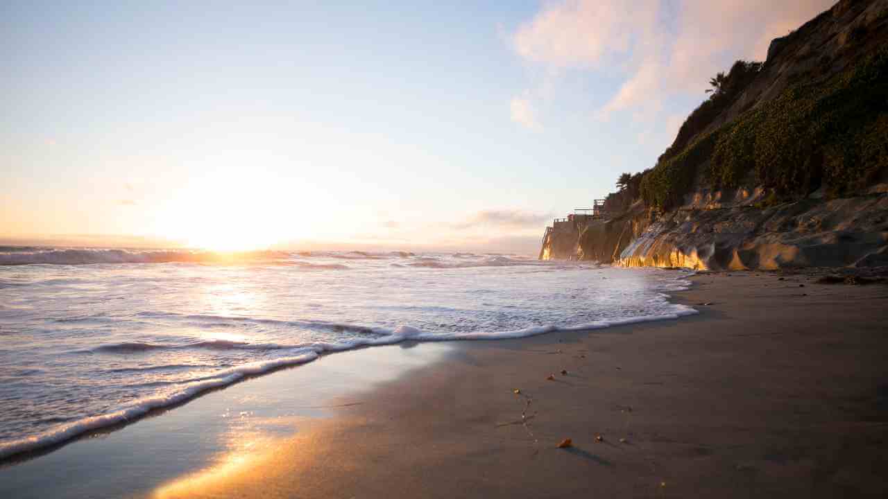 the sun is setting over the ocean at the beach